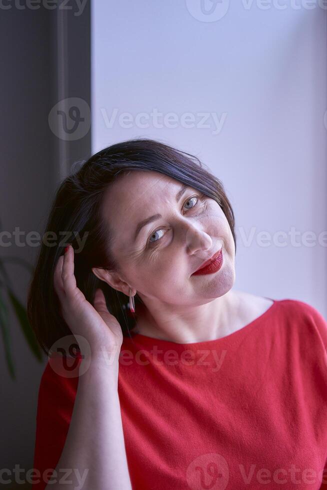 Porträt von ein Brünette mit ein Bob Haarschnitt im ein rot Sweatshirt und ein Leder Mini Rock im das Büro foto