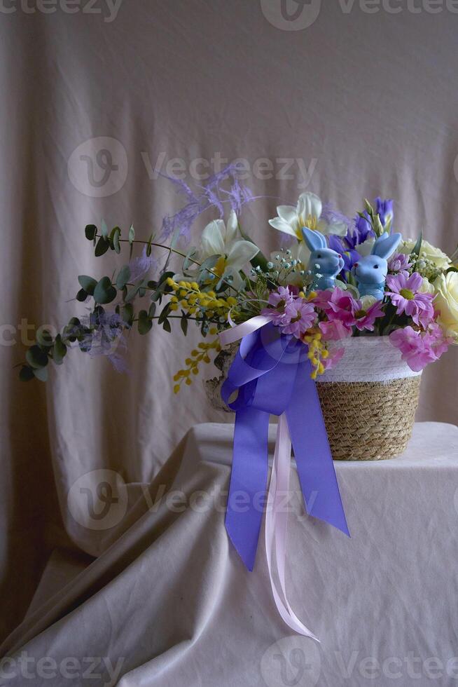 Ostern Blumen- Anordnung mit zwei Blau Ostern Hasen im ein Korbweide Korb foto