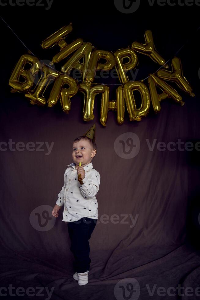 ein Kleinkind im ein Party Deckel weht ein pfeifen Flöte foto