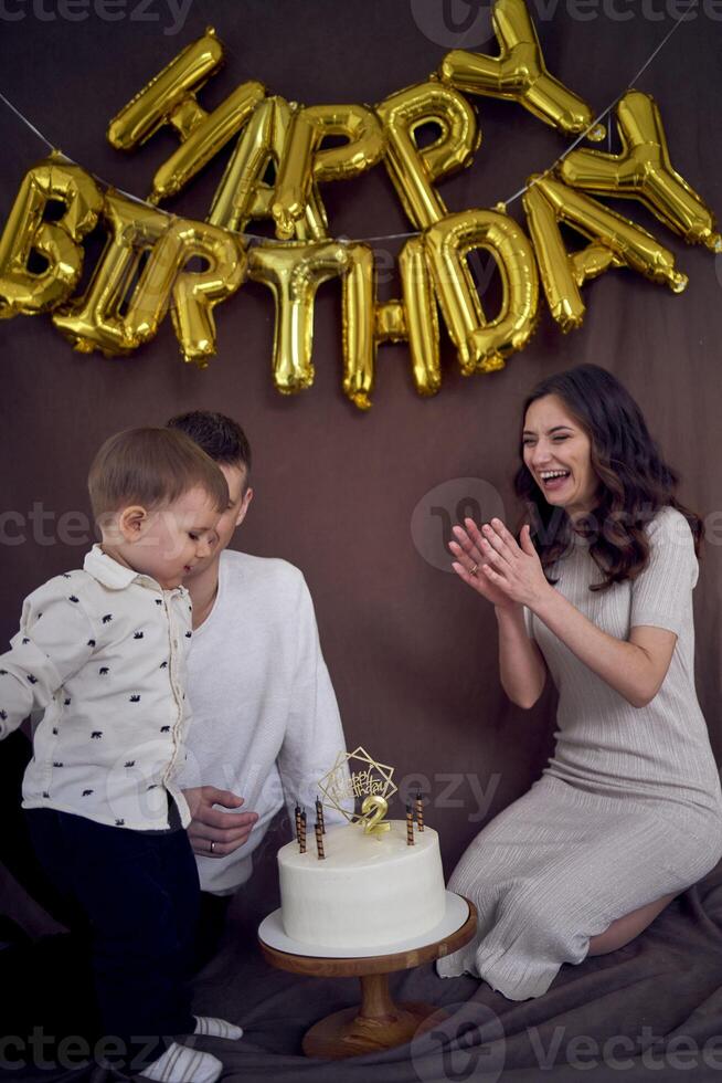 emotional Eltern Uhr wie ihr Sohn weht aus das Kerzen auf das Geburtstag Kuchen foto
