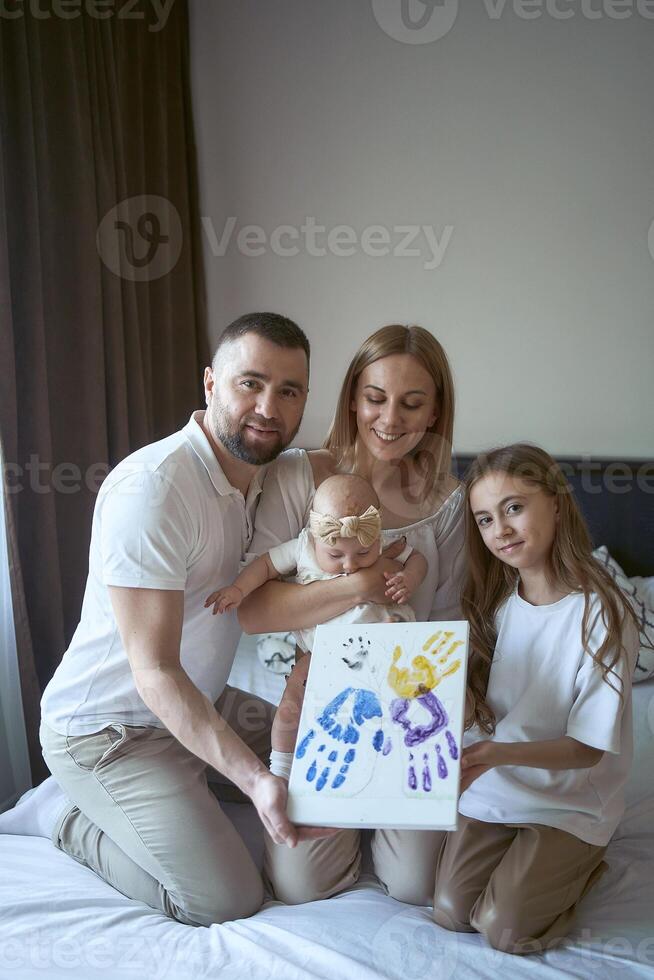 Familie hält ein Gemälde mit ihr Hand druckt foto