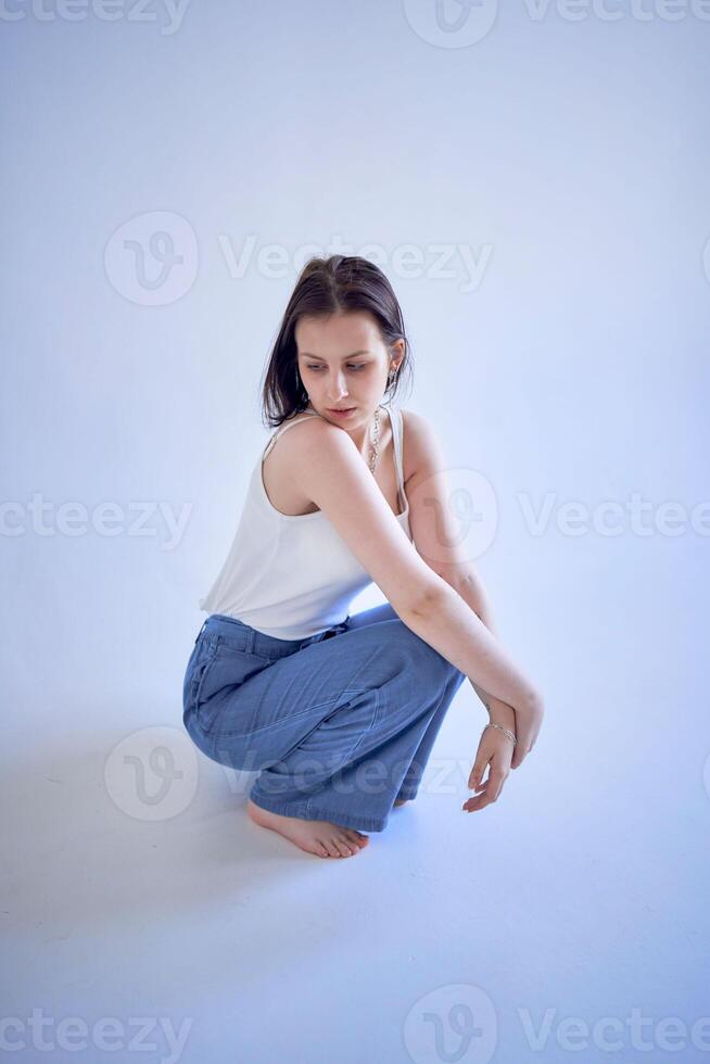 jung Teenager Mädchen sitzt auf ein Weiß Rundhorizont im das Studio foto