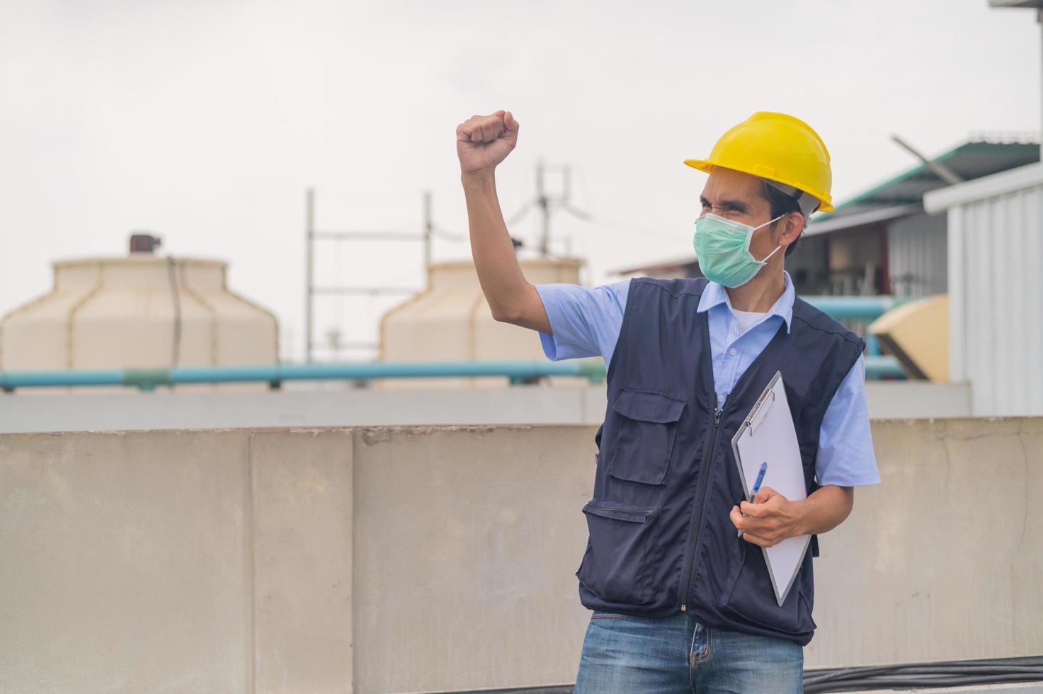 Ingenieur steht auf dem Dach des Produktionsgebäudes zeigt Engagement und Erfolg foto