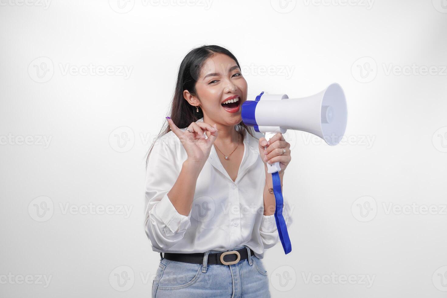 aufgeregt asiatisch Frau im beiläufig formal Outfit halten und schreien beim Megaphon, zeigen wenig Finger eingetaucht im lila Tinte nach Wählen zum Indonesien Wahl, Stehen auf isoliert Weiß Hintergrund foto