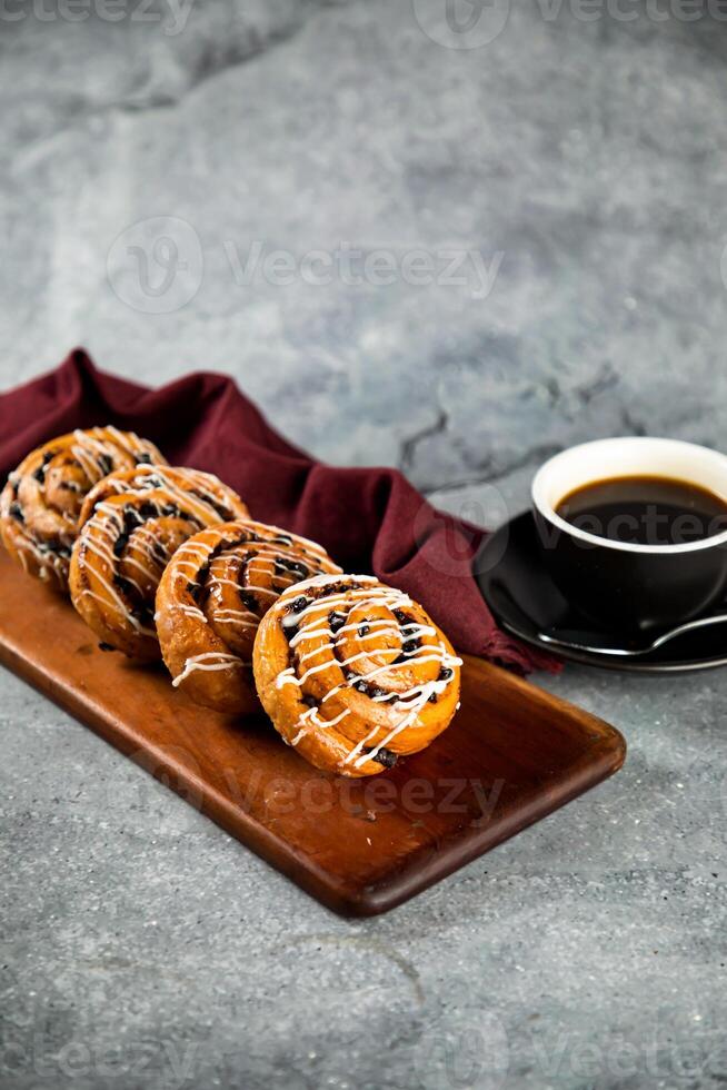 Schokolade rollen serviert auf hölzern Tafel mit Tasse von schwarz Kaffee isoliert auf Serviette Seite Aussicht von Französisch Frühstück gebacken Essen Artikel foto