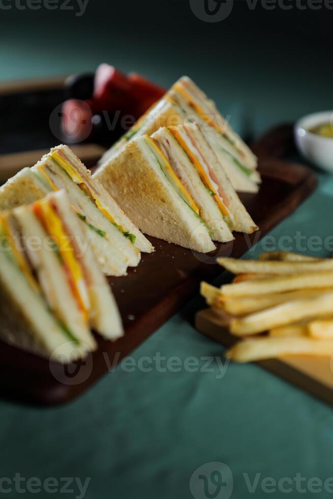 sortiert Verein Sandwich isoliert auf hölzern mit Mayonnaise tauchen und Französisch Fritten Eimer Tafel Seite Aussicht von Italienisch schnell Essen auf Hintergrund foto