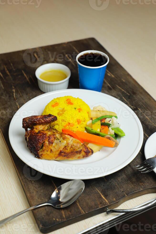 Reis mit Hähnchen braten Mahlzeit mit Salat serviert im Teller mit Soße, kalt trinken, Löffel und Gabel isoliert auf hölzern Tafel Seite Aussicht von thailändisch Essen foto