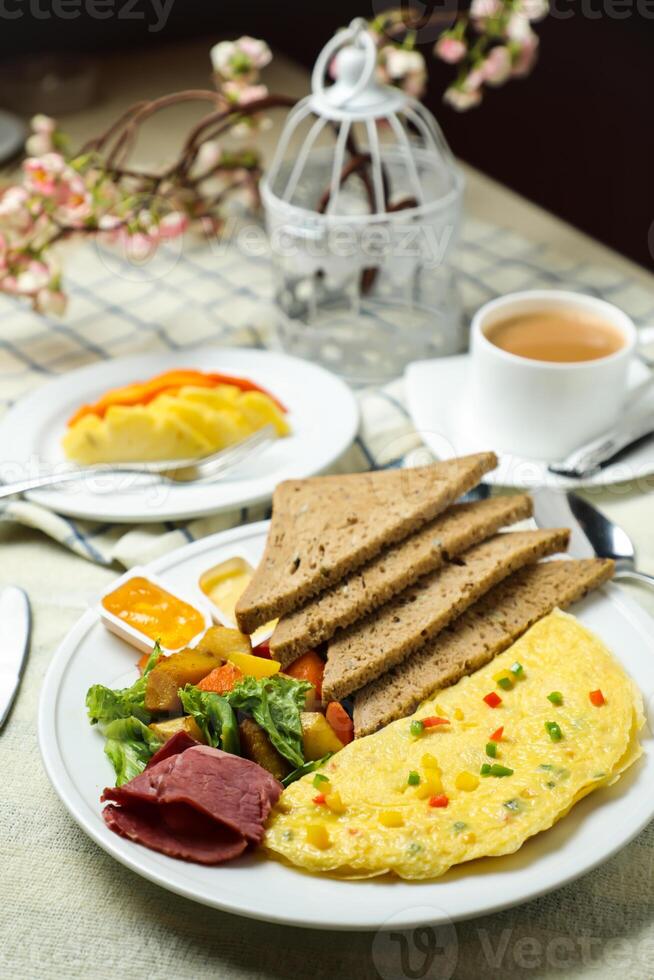 ausgestopft Omelette mit bown brot, Fleisch, Gemüse Salat umfassen Tomate, Kartoffel, Grüner Salat Blatt und Karotte mit Tee, Kaffee, und Süss Melone serviert auf Essen Tabelle oben Aussicht gesund Frühstück foto