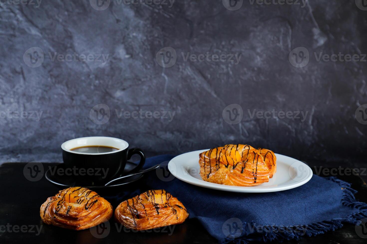 Pfirsich dänisch Gebäck Puff serviert im Teller mit Tasse von schwarz Kaffee isoliert auf Serviette Seite Aussicht von Französisch Frühstück gebacken Essen Artikel auf grau Hintergrund foto