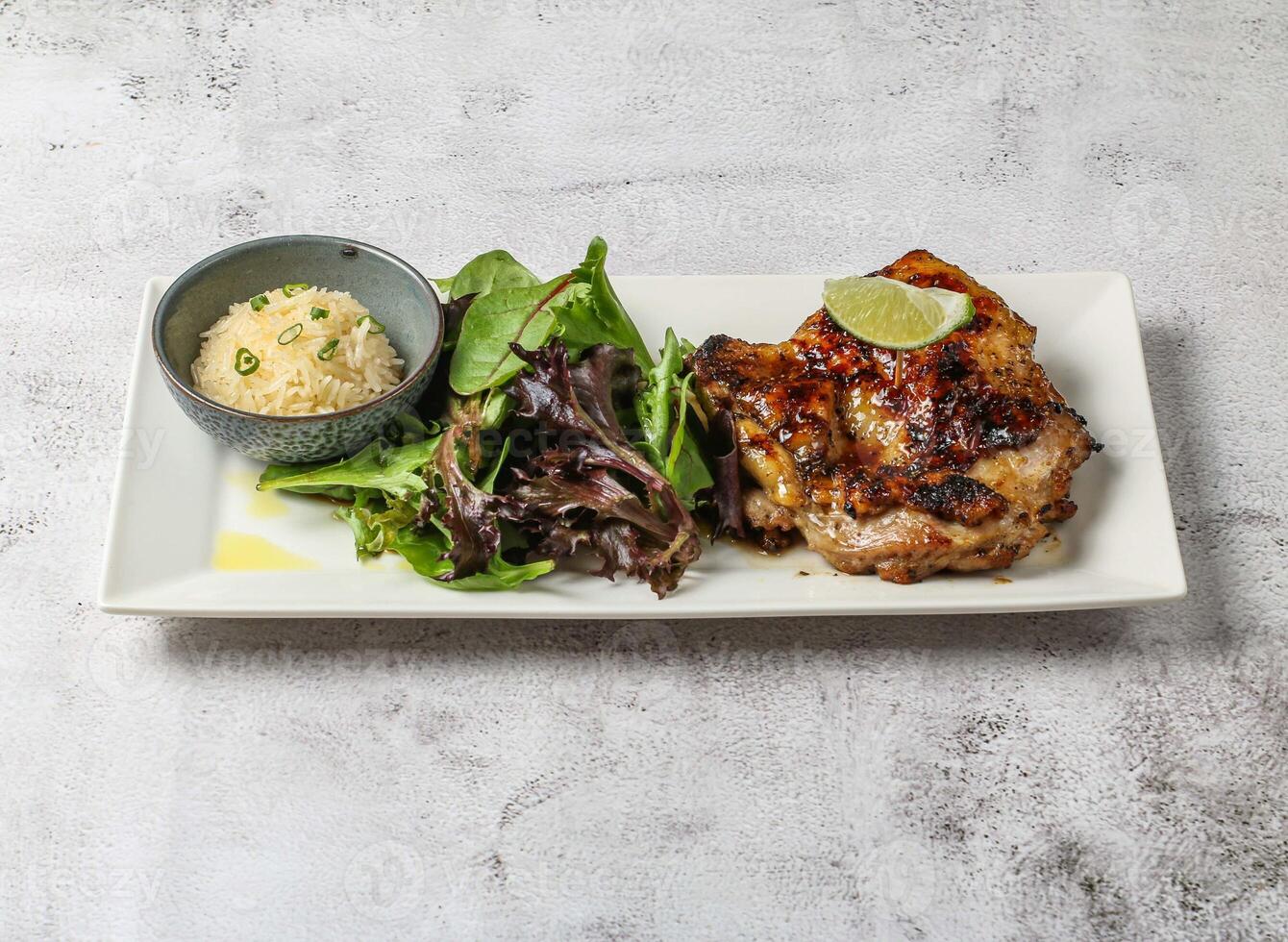 Chao ta gegrillt Hähnchen Steak mit einfach Reis, Zitrone und Grün Blätter serviert im Gericht isoliert auf grau Hintergrund oben Aussicht von Singapur Essen foto