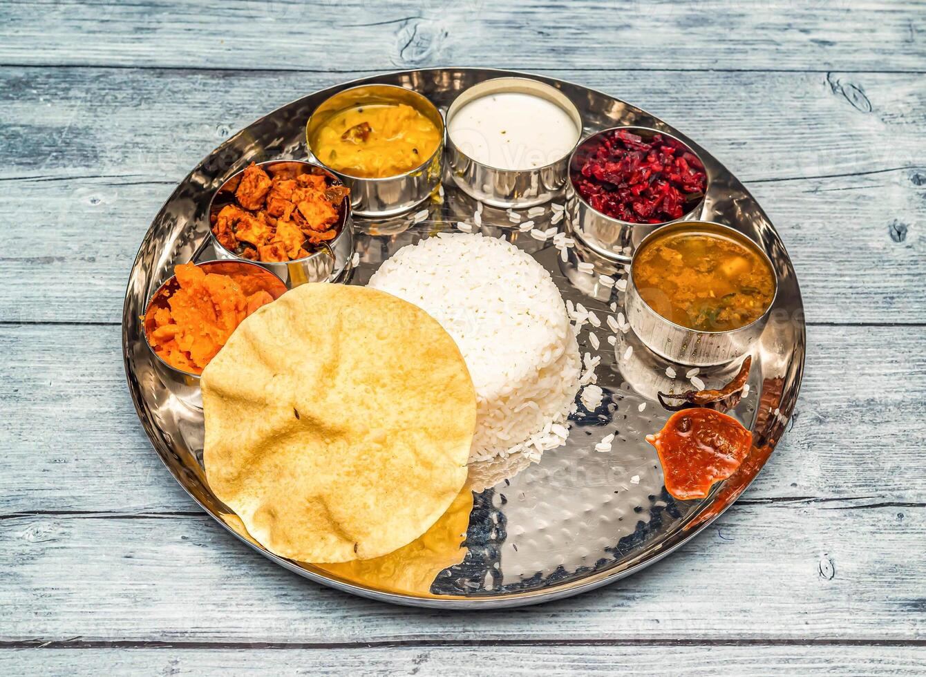 Süd indisch Vegetarier Mahlzeit Thali Gemüse, Curry, Reis, Raita, Korma, kesari halwa und Chapati serviert im Gericht isoliert auf hölzern Tabelle oben Aussicht von indisch würzig Essen foto