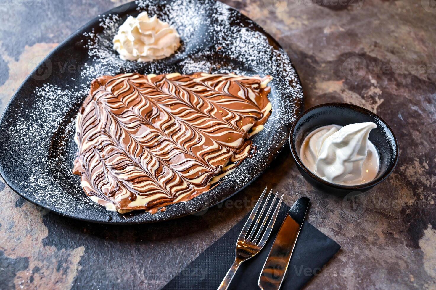 heiß Schokolade Krepp Marmor Design mit ausgepeitscht Creme, Messer und Gabel serviert im Gericht isoliert auf dunkel Hintergrund Nahansicht oben Aussicht von Cafe gebacken Dessert Essen foto