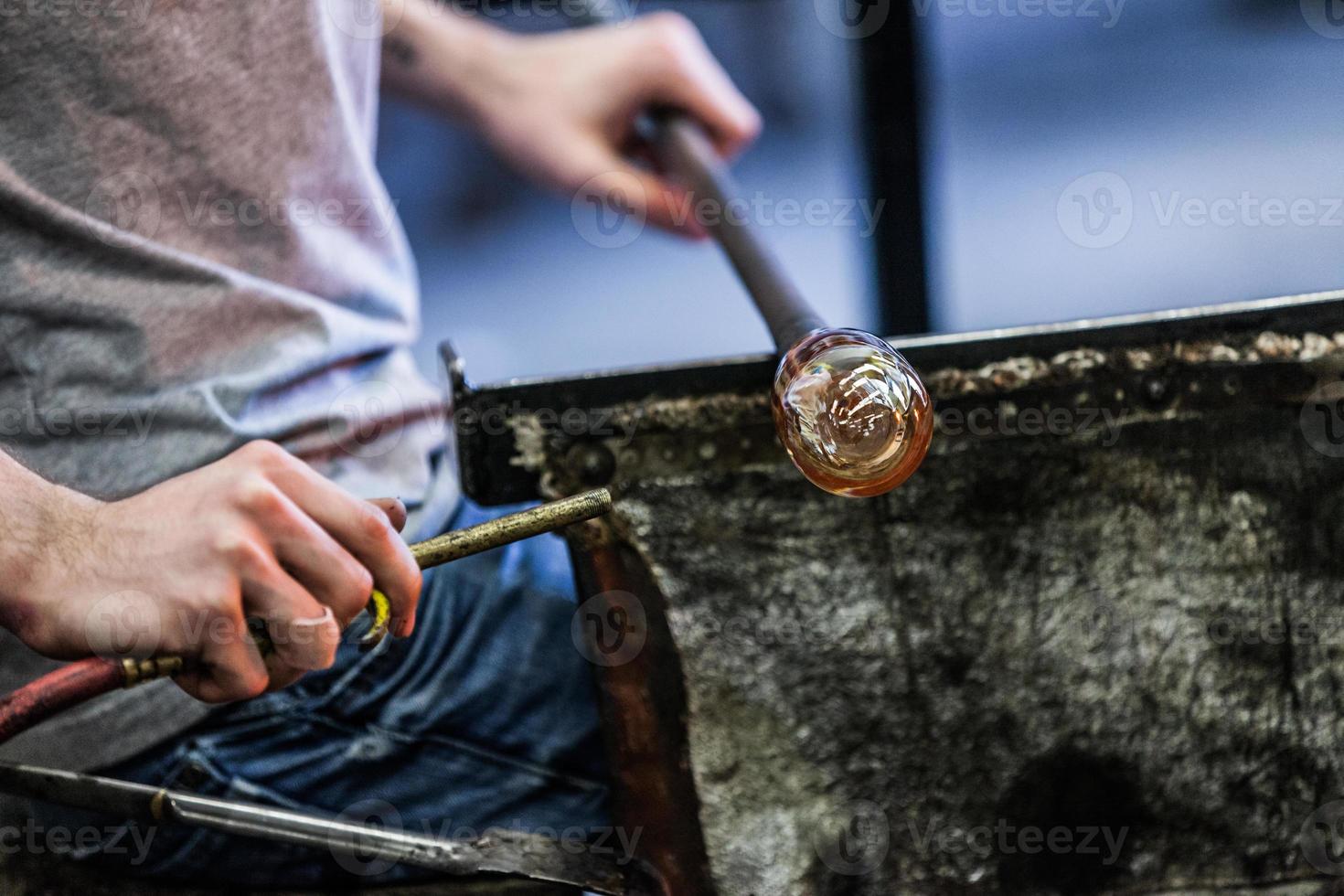 Mannhände Nahaufnahme, die an einem mundgeblasenen Glasstück arbeiten foto
