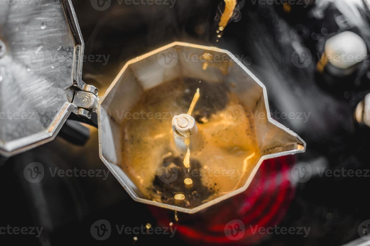 Italienische Aluminium-Kaffeemaschine, die einen frischen dunklen Kaffee auf dem Herd brüht foto