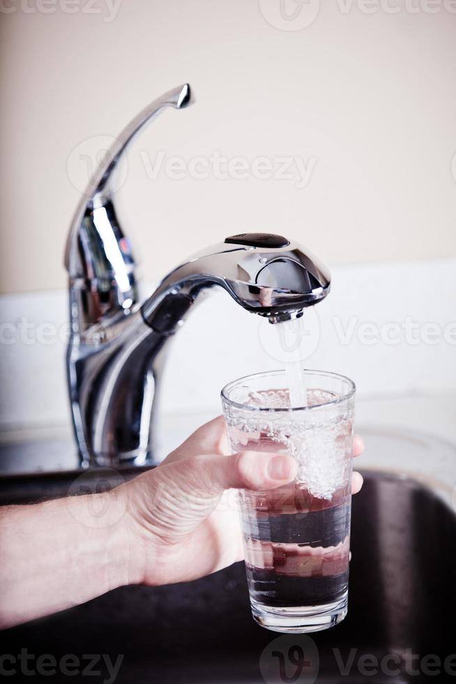 durstiger Mann füllt ein großes Glas Wasser foto