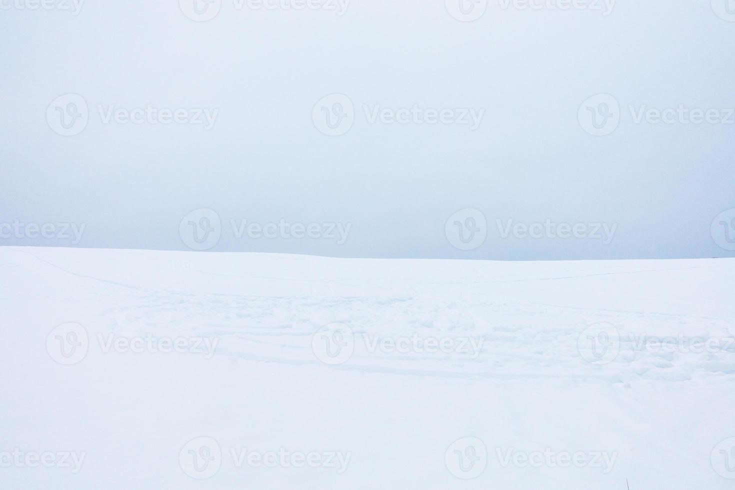 weiche minimalistische Landschaft des Schneefeldes mit Schneemobilspuren. foto