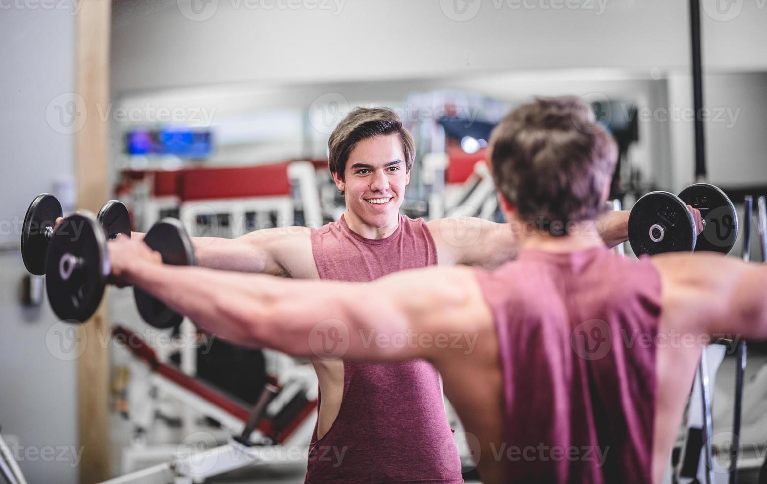 muskulöser gutaussehender Mann mit Hanteln im Fitnessstudio foto