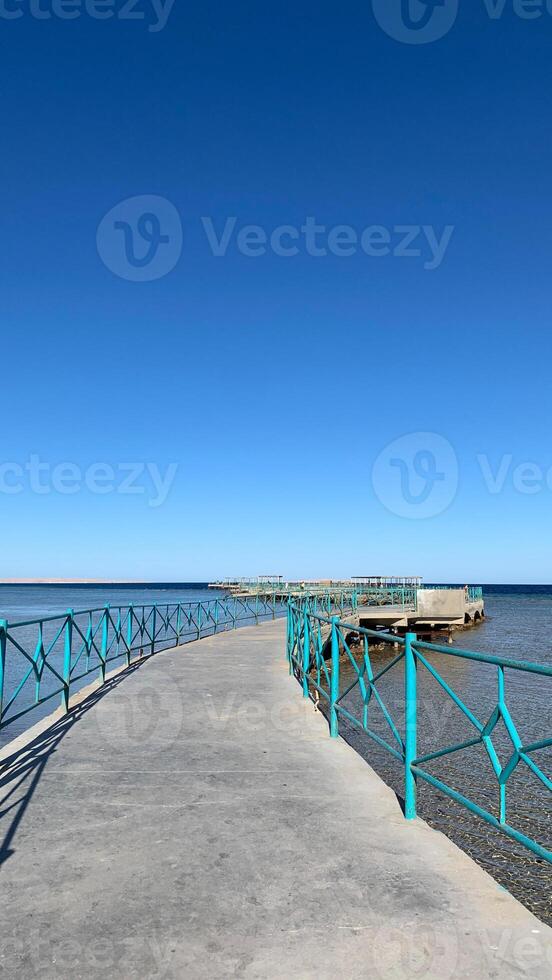 Vertikale Foto von Seebrücke zum gehen durch das Meer gegen das Hintergrund von klar Blau Himmel auf heiß Sommer- Tag