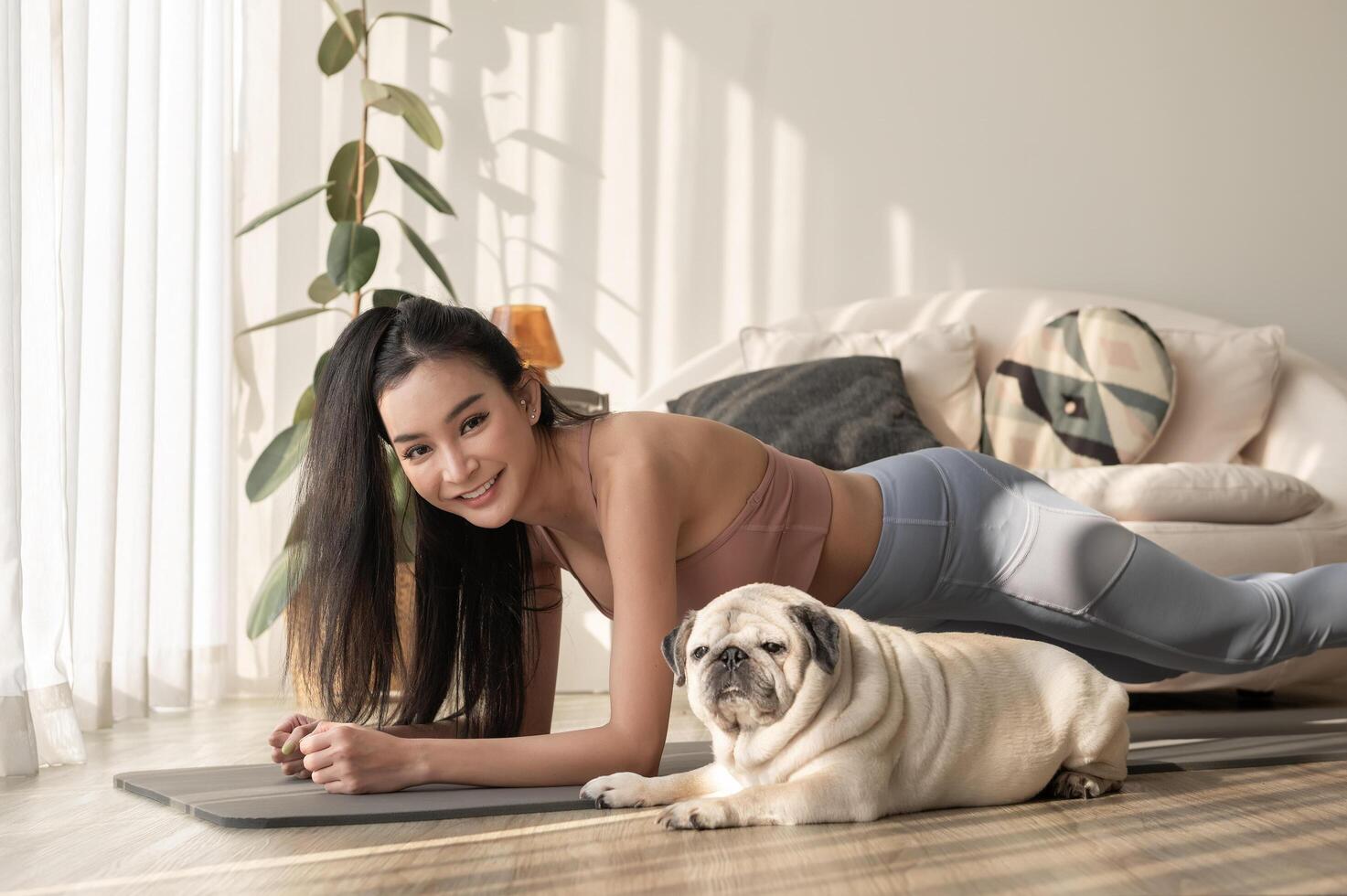 asiatisch Frau im Sportbekleidung ausüben und tun Yoga mit süß Hund im Leben Zimmer beim heim, gesund Lebensstil, mental Gesundheit Konzept. foto