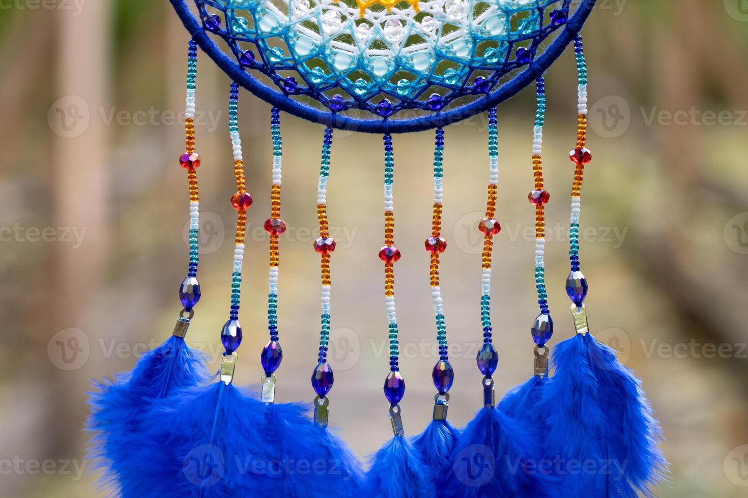 handgefertigter Traumfänger mit Federn, Fäden und Perlen am Seil hängend foto