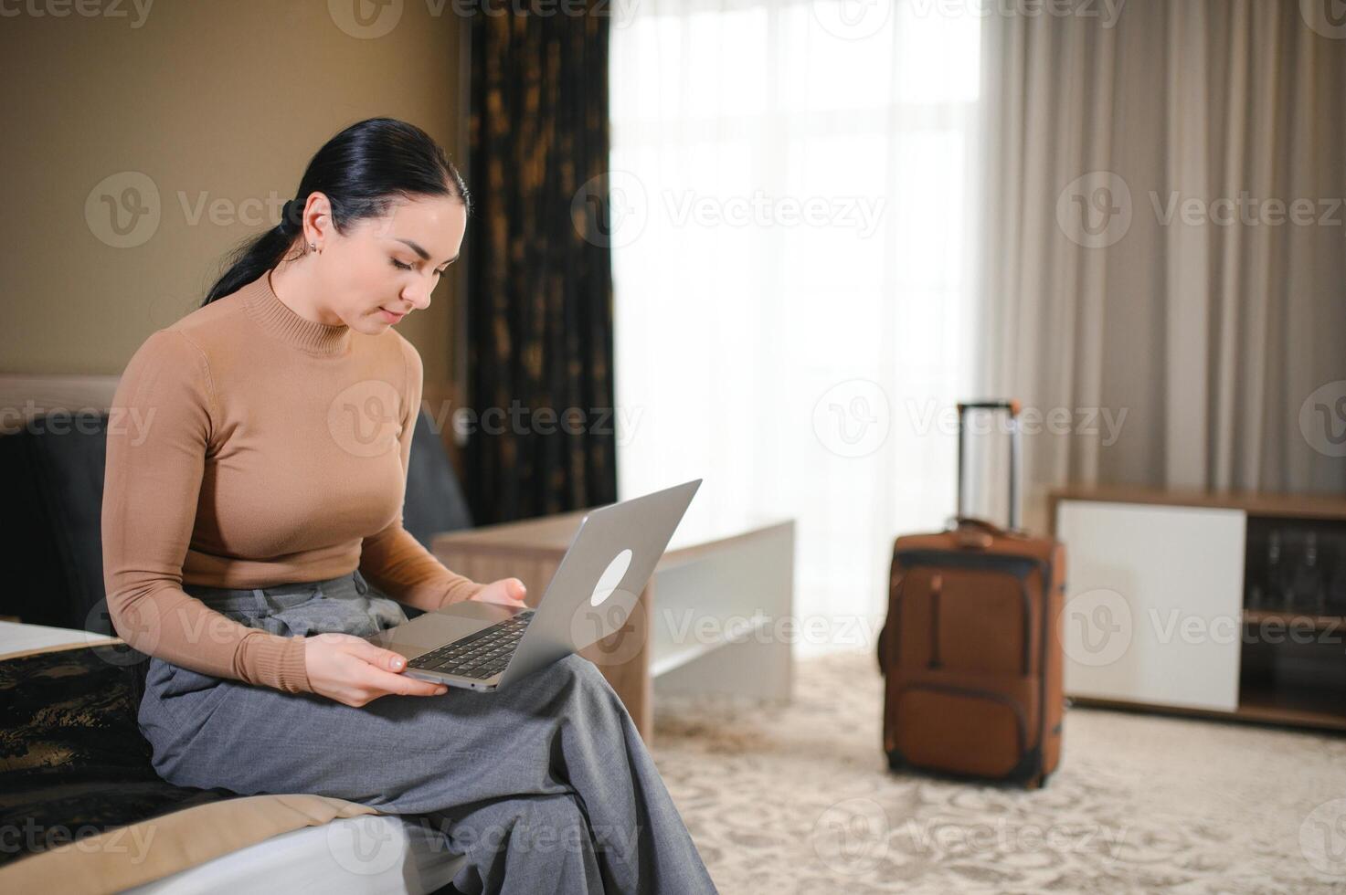 jung Geschäftsfrau Arbeiten von Hotel Zimmer auf Geschäft Reise, Frau Sitzung auf Bett und mit Laptop foto