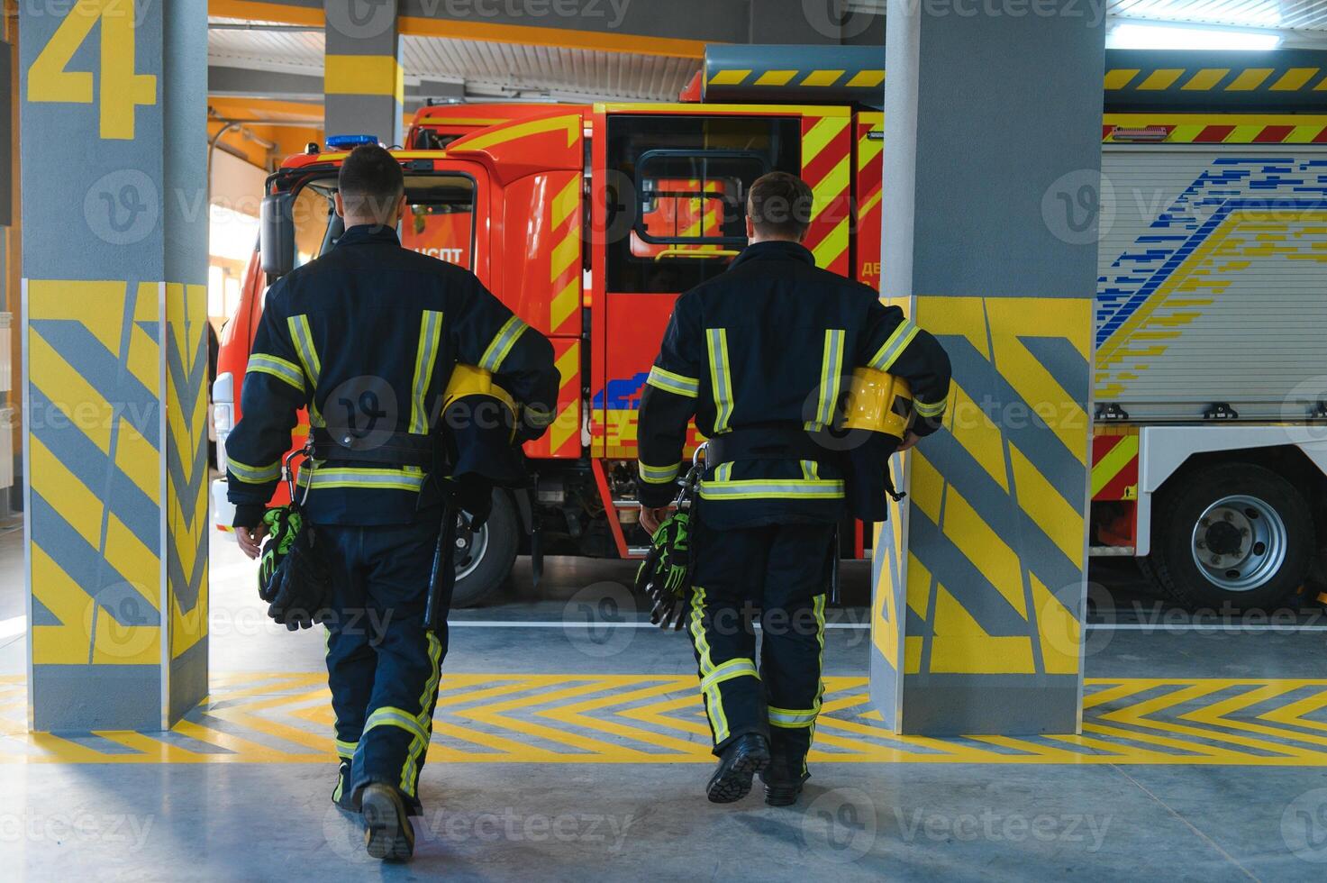 Porträt von zwei jung Feuerwehrmänner im Uniform Stehen Innerhalb das Feuer Bahnhof foto