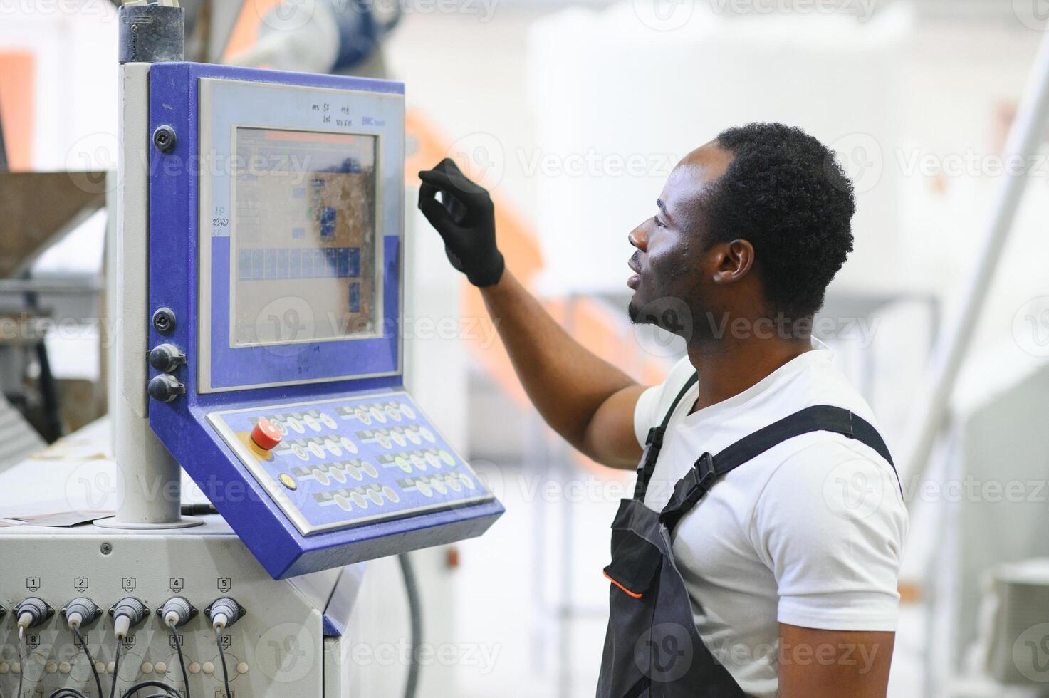 Porträt von afrikanisch amerikanisch männlich Ingenieur im Uniform und Stehen im industriell Fabrik foto