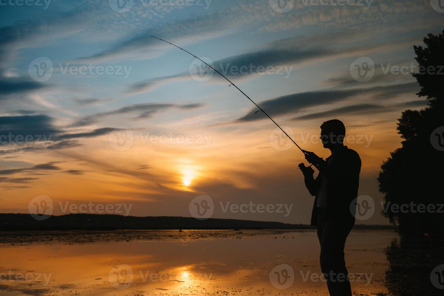Fischer beim Sonnenuntergang auf das Fluss .Schön Sommer- Landschaft mit Sonnenuntergang auf das Fluss. Angeln. Spinnen beim Sonnenuntergang. Silhouette von ein Fischer. foto