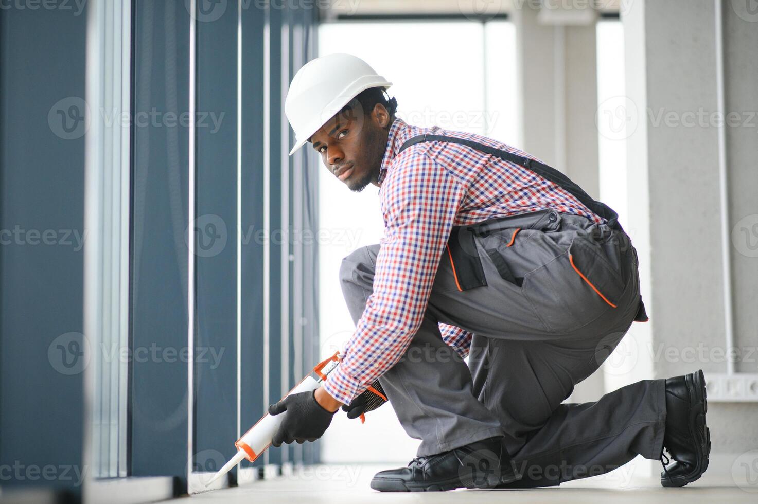 niedrig Winkel Aussicht von ein jung afrikanisch Handwerker im Overall Installation Fenster foto