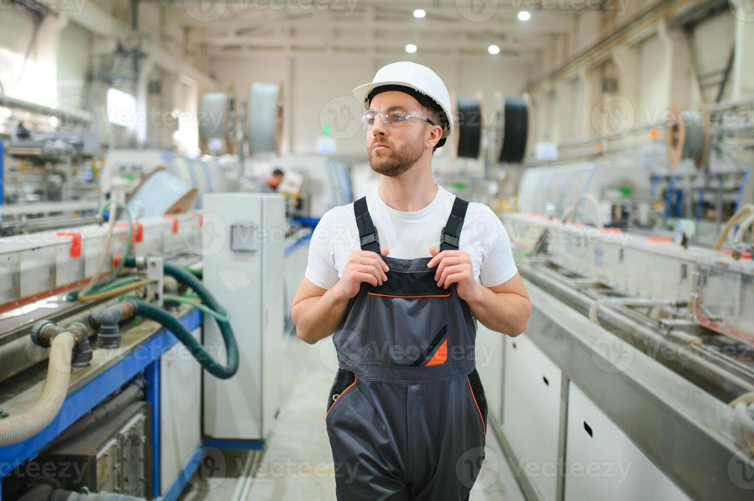 lächelnd und glücklich Mitarbeiter. industriell Arbeiter drinnen im Fabrik. jung Techniker mit schwer Hut foto