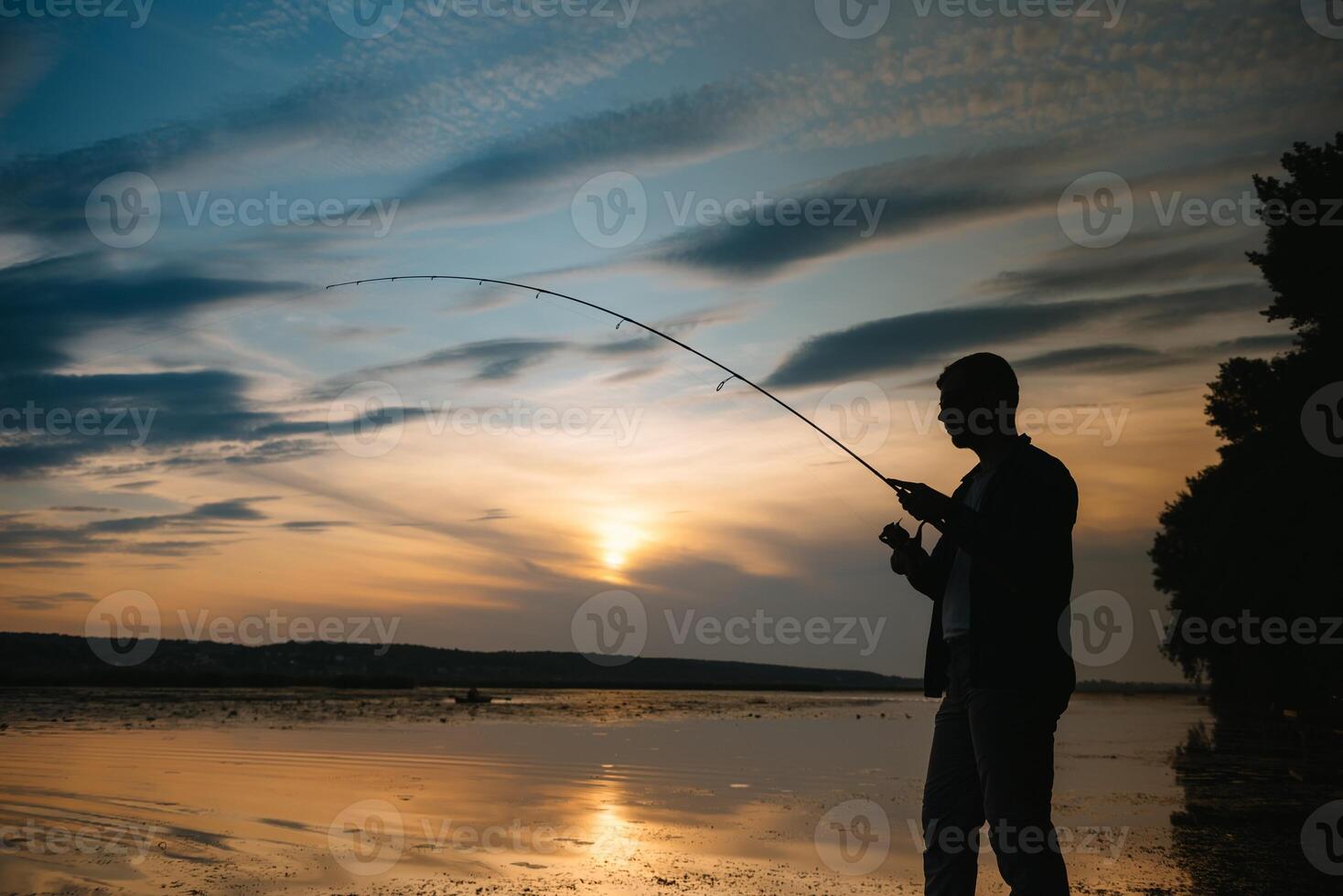 Fischer beim Sonnenuntergang auf das Fluss .Schön Sommer- Landschaft mit Sonnenuntergang auf das Fluss. Angeln. Spinnen beim Sonnenuntergang. Silhouette von ein Fischer. foto