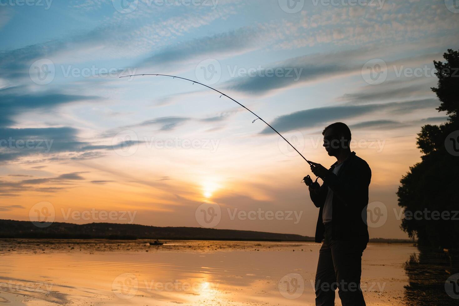 Angeln. Spinnen beim Sonnenuntergang. Silhouette von ein Fischer foto