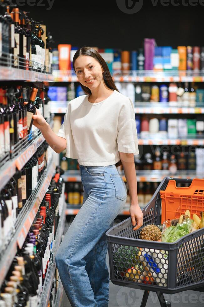 Mädchen wählt Wein im Supermarkt foto