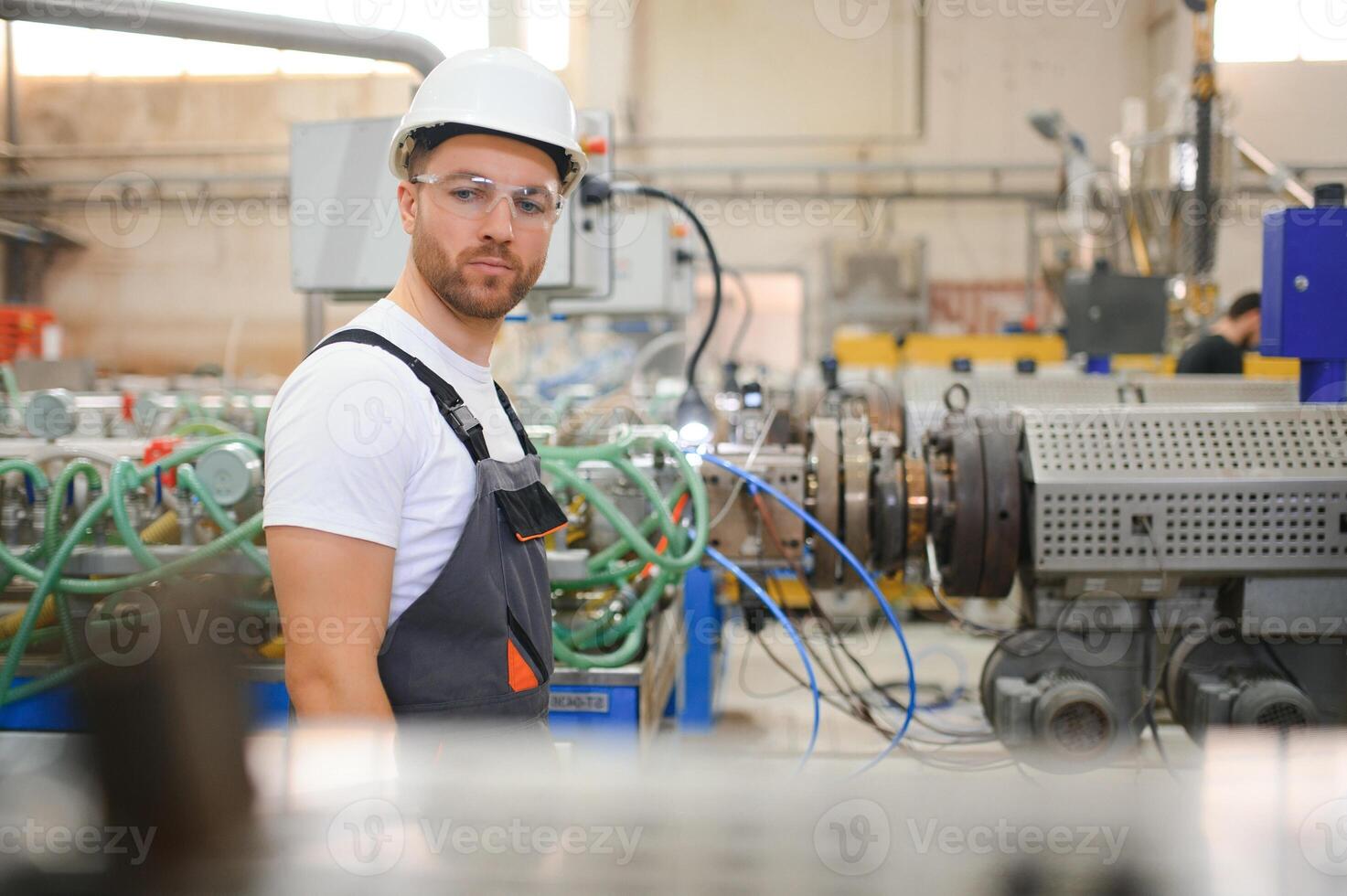 lächelnd und glücklich Mitarbeiter. industriell Arbeiter drinnen im Fabrik. jung Techniker mit schwer Hut foto