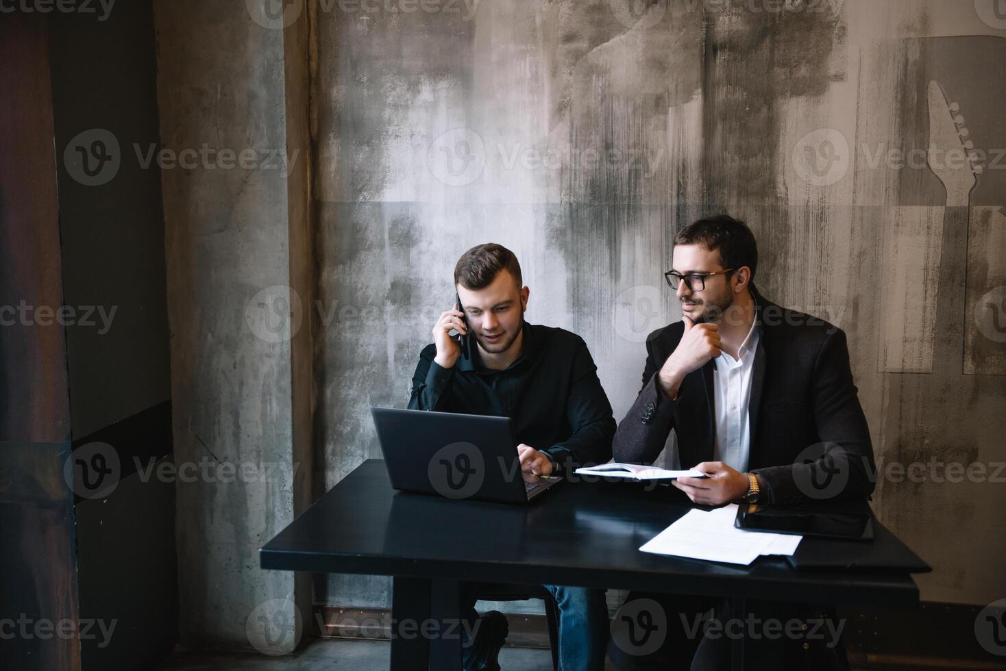 zwei Geschäftsleute im ein Büro lächelnd beim das Kamera während Arbeiten zusammen hinter ein Laptop Computer. foto