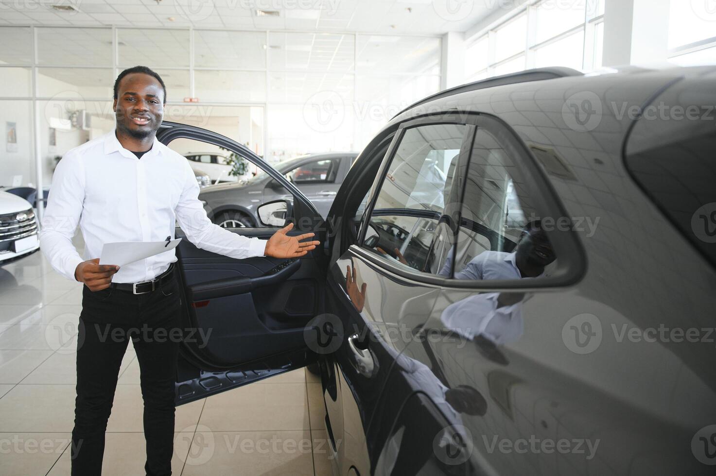 Porträt von gut aussehend afrikanisch amerikanisch Verkäufer beim Arbeitsplatz im Auto Ausstellungsraum foto