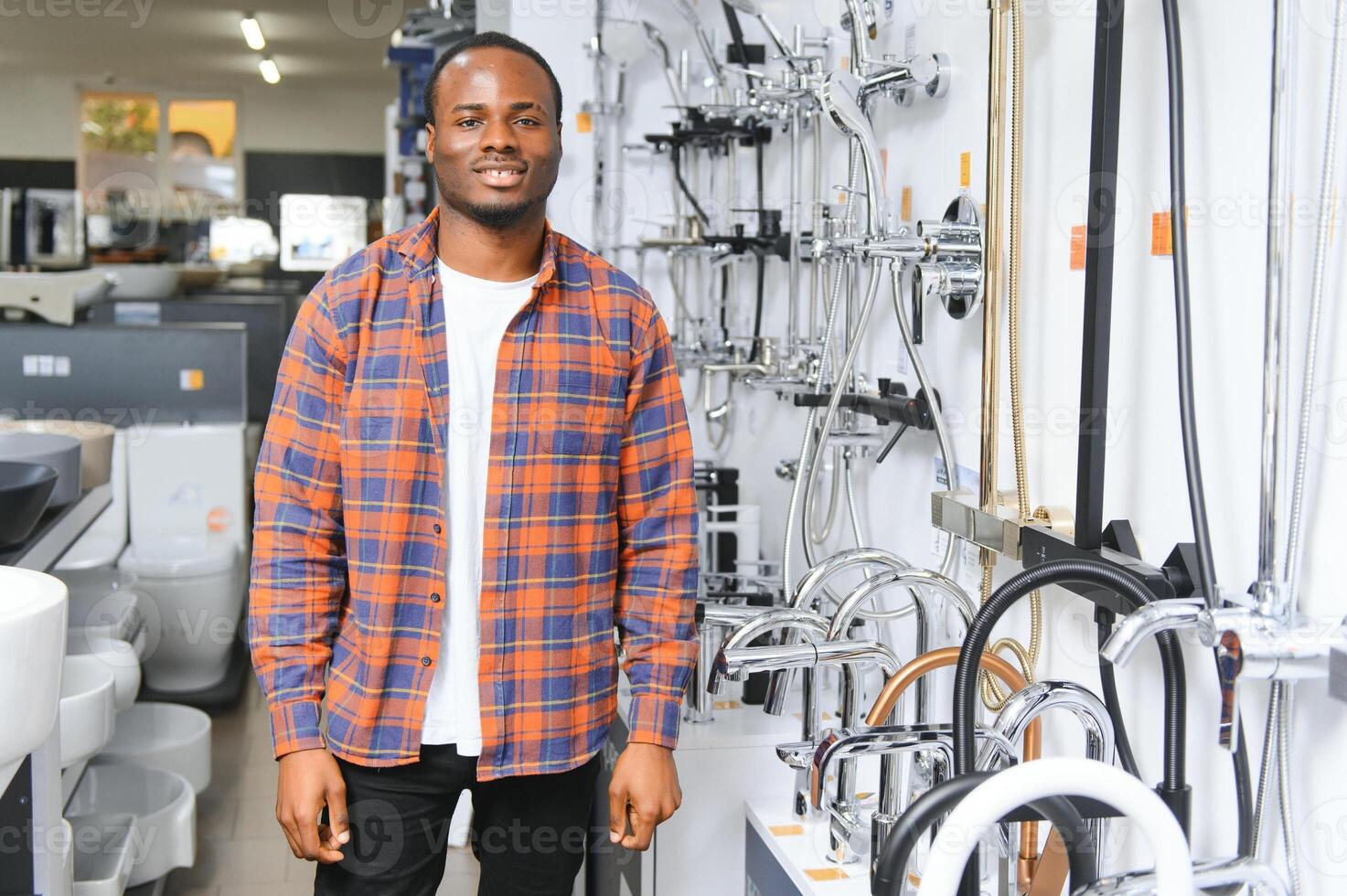 afrikanisch Mann im ein braun Mantel wählt ein Badezimmer Wasserhahn im ein Konstruktion Supermarkt, Installation Instandsetzung im das Haus foto