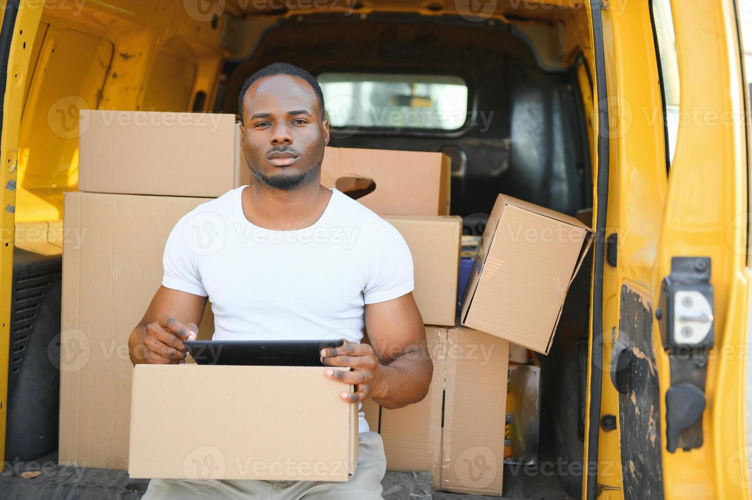 Porträt von ein jung afrikanisch amerikanisch Paket Lieferung Mann in der Nähe von ein Auto mit Boxen. foto