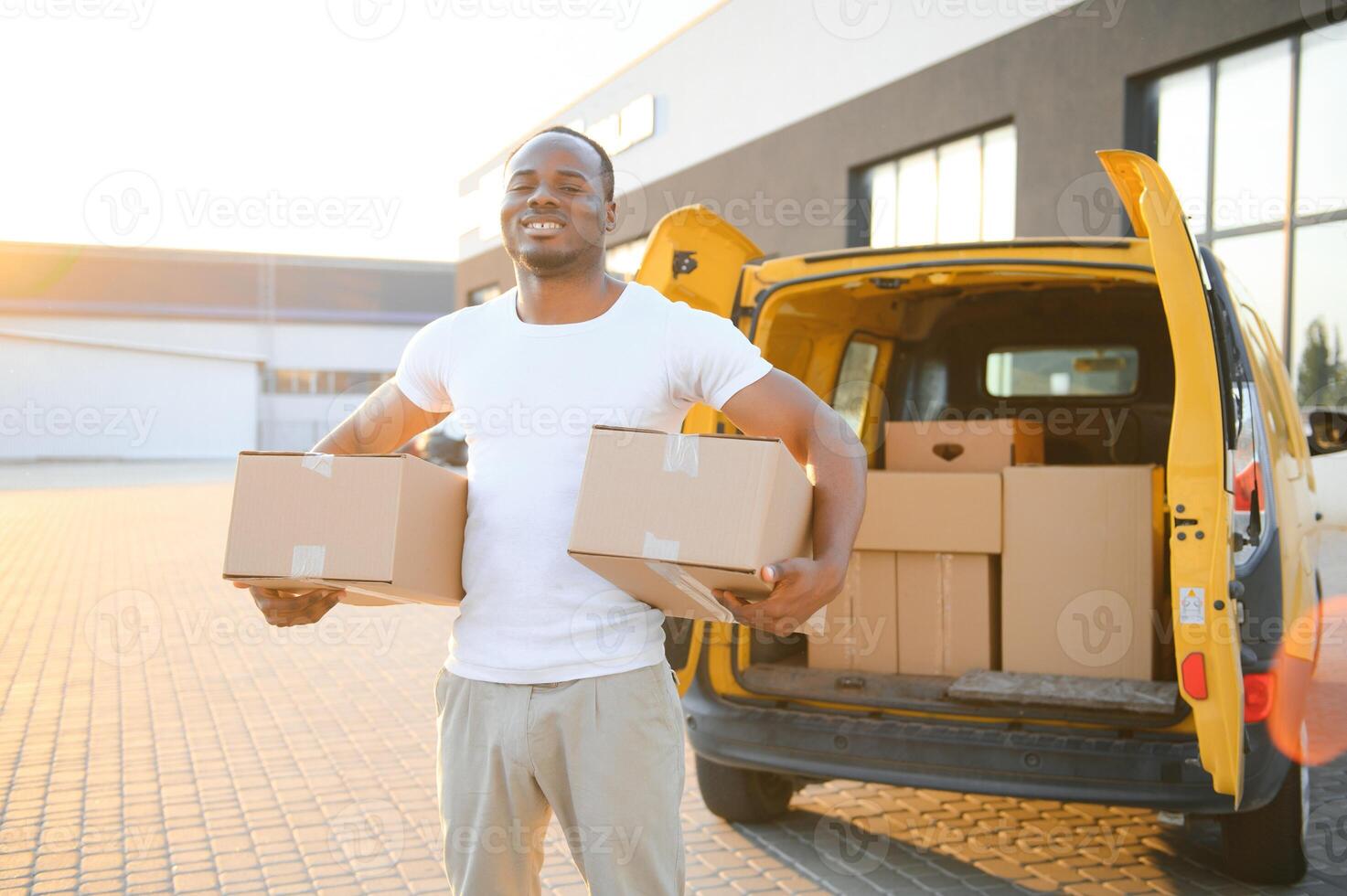 Porträt von ein jung afrikanisch amerikanisch Paket Lieferung Mann in der Nähe von ein Auto mit Boxen. foto