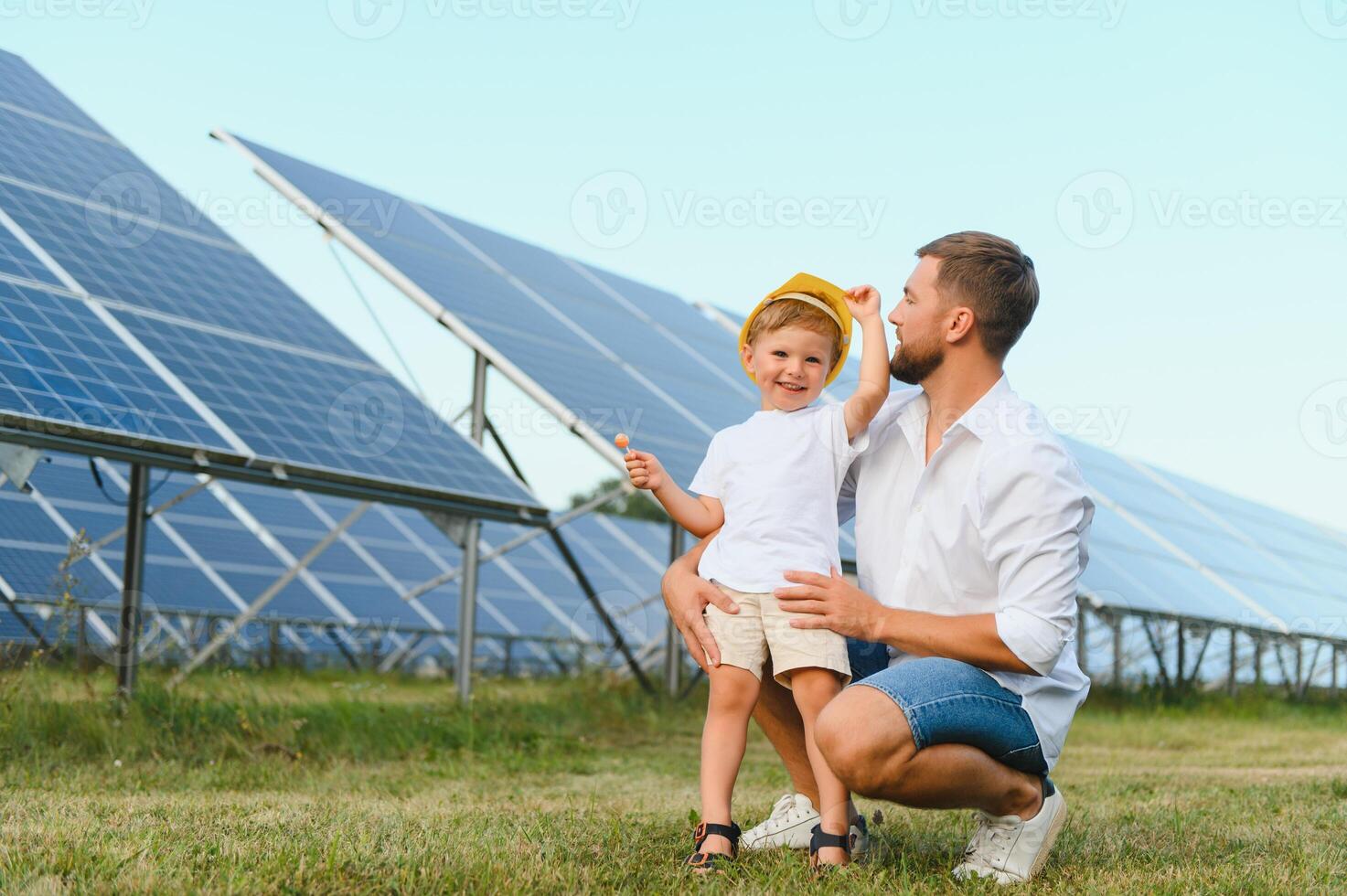 ein Vater und seine wenig Sohn in der Nähe von das Solar- Tafeln. ein wenig Junge im ein Gelb Helm foto