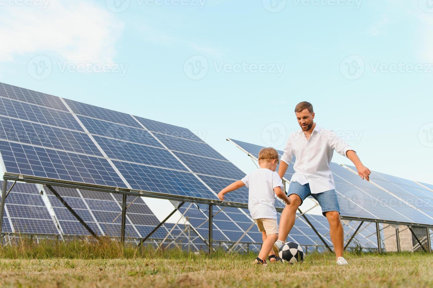 Vater und Sohn haben Spaß spielen Fußball in der Nähe von das Solar- Tafeln. das Konzept von Grün Energie foto