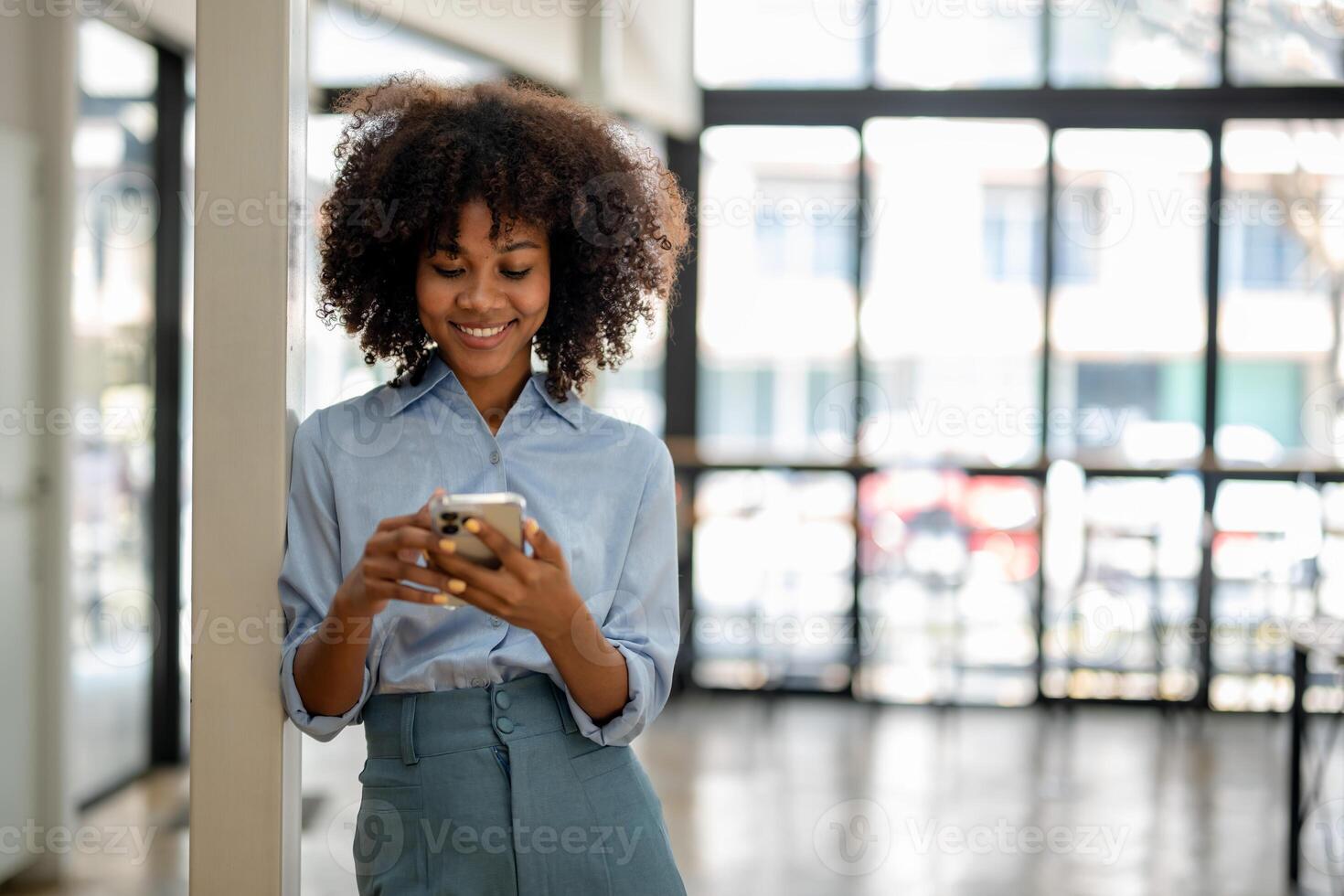 Porträt von lächelnd schwarz Frau mit Clever Telefon genießt online chatten Typen Text Botschaft surft Sozial Netzwerke foto