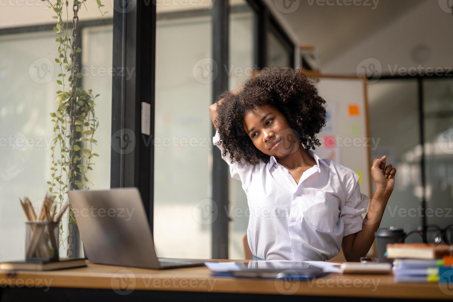 schwarz Frau bekommen physisch aktiv von ermüden Sitzung beim ein Schreibtisch. müde von arbeiten, Verdrehen fällig zu Schmerz, Büro Syndrom von Büro Arbeitskräfte foto