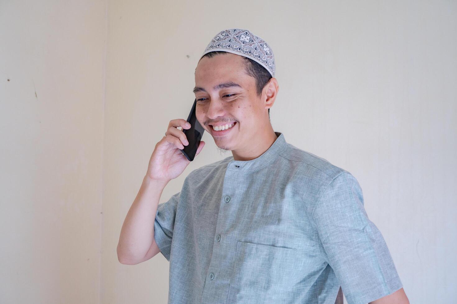 Moslem asiatisch Mann Berufung mit Smartphone mit glücklich Gesicht wann Ramadan Feier. das Foto ist geeignet zu verwenden zum Ramadhan Poster und Muslim Inhalt Medien.