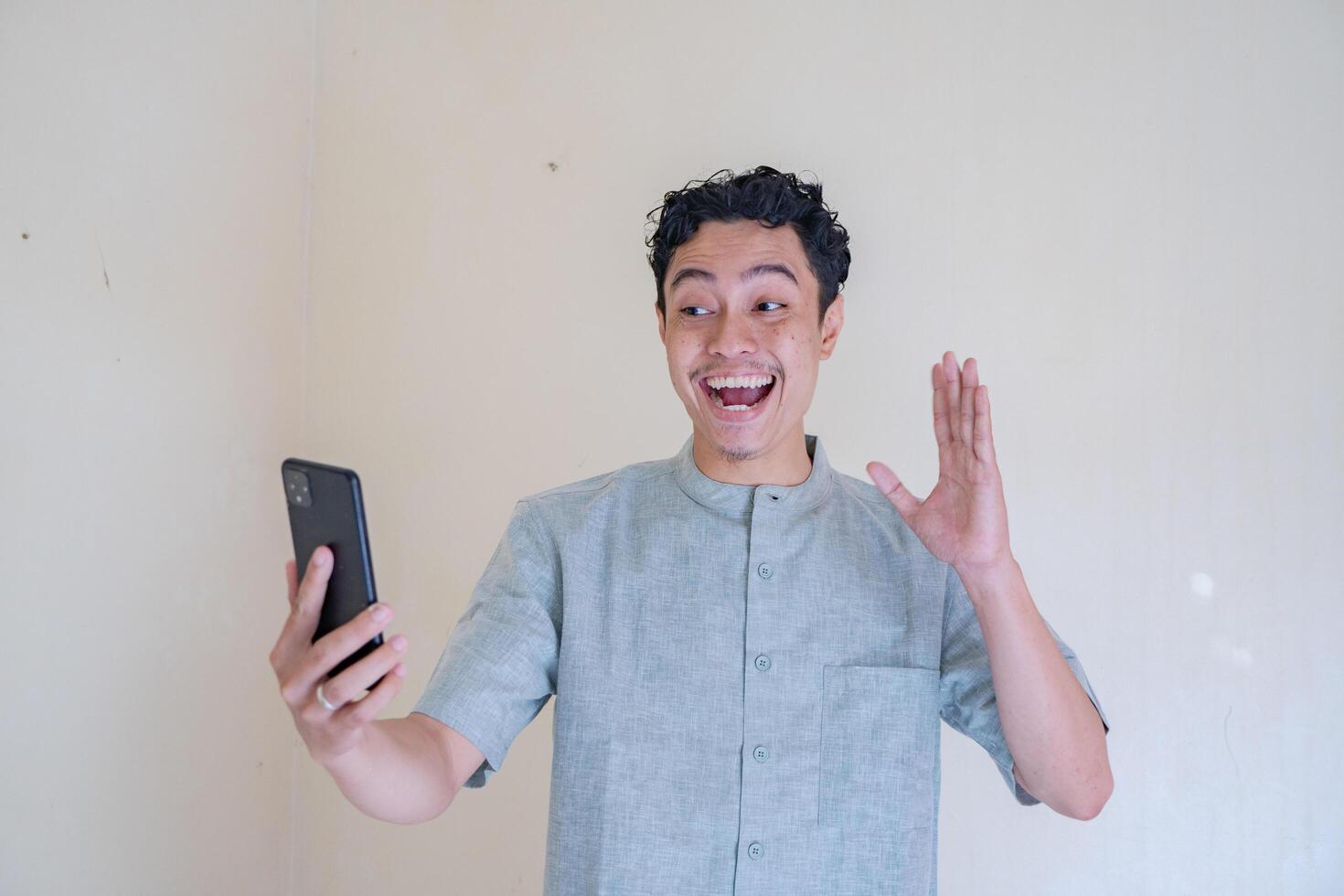 Moslem asiatisch Mann glücklich während Anruf mit Smartphone wann Ramadan Feier. foto
