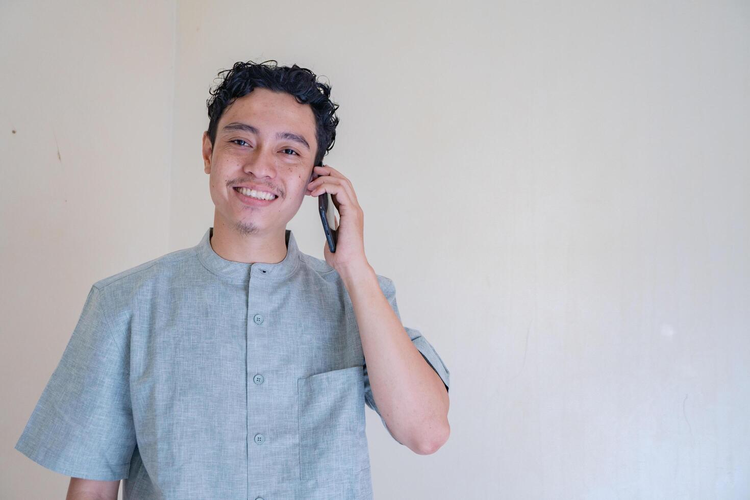 Moslem asiatisch Mann Berufung mit Smartphone mit glücklich Gesicht wann Ramadan Feier. das Foto ist geeignet zu verwenden zum Ramadhan Poster und Muslim Inhalt Medien.