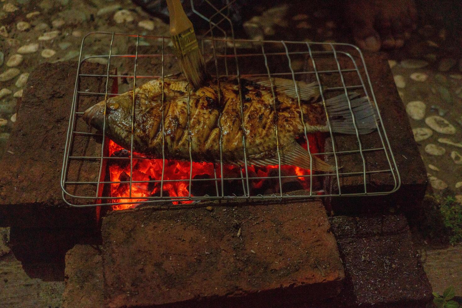 Fisch gegrillt Über das Holzkohle Feuer wann Sommer- Party. das Foto ist geeignet zu verwenden zum gegrillt Inhalt Medien und Party Poster.