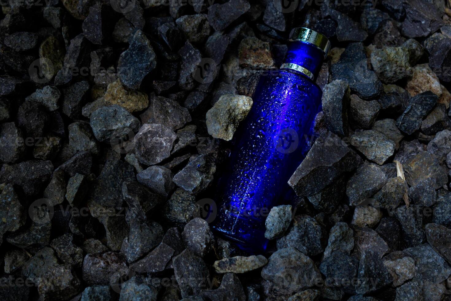 Parfüm dunkel Blau transparent Flasche im Kies oder Koralle Hintergrund foto