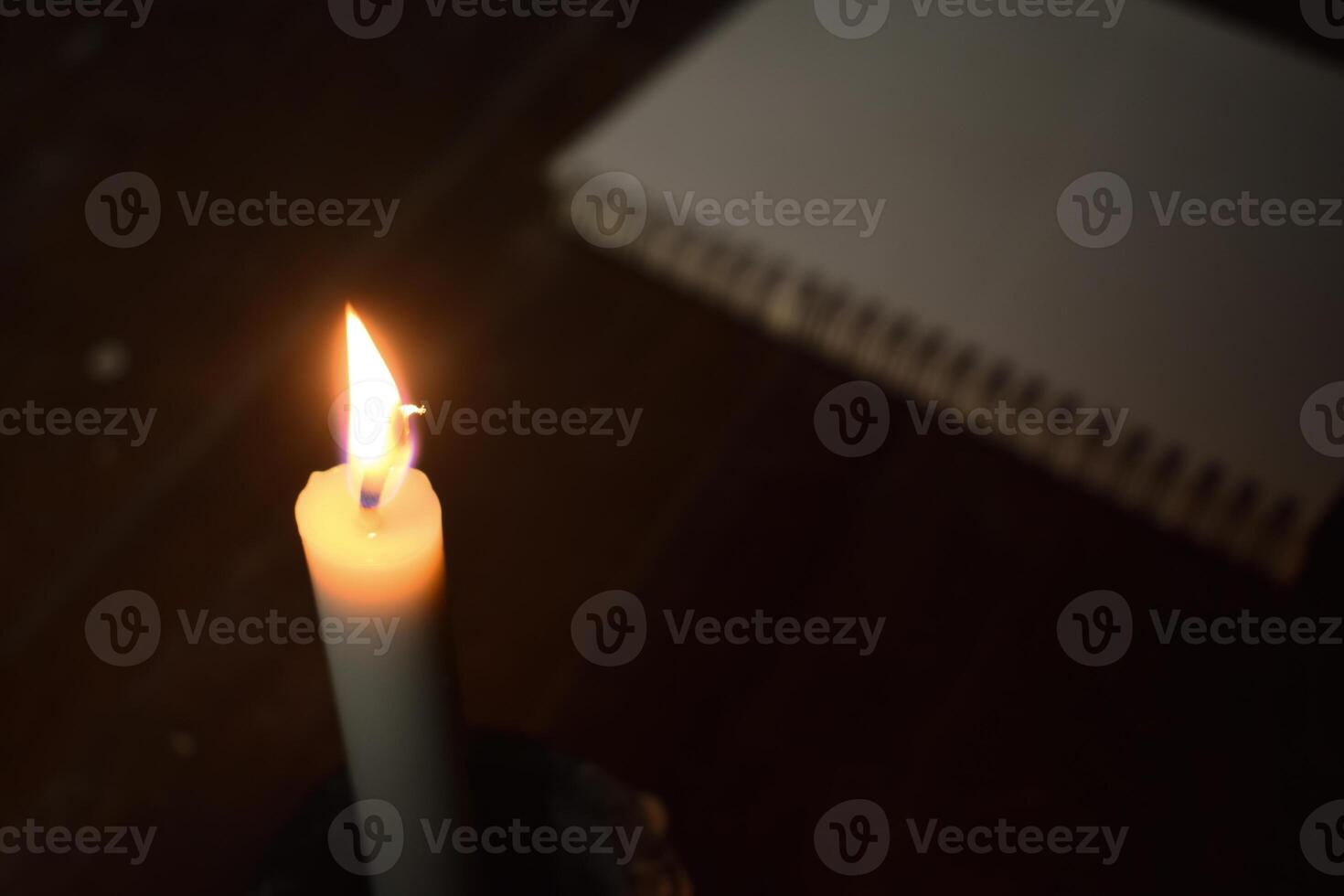 Single Kerze mit Flamme im das dunkel Platz mit Buch verwischen Hintergrund foto
