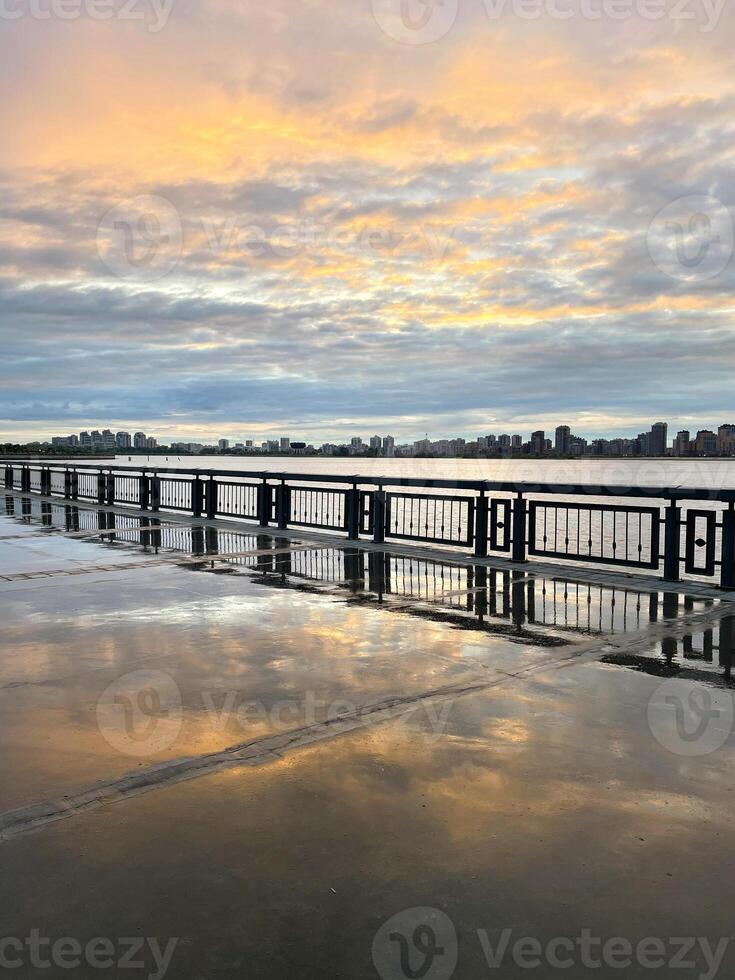 Sonnenuntergang auf das Damm nach das Regen. Betrachtung von das Himmel im das nass Gehweg, Kasan, Russland foto